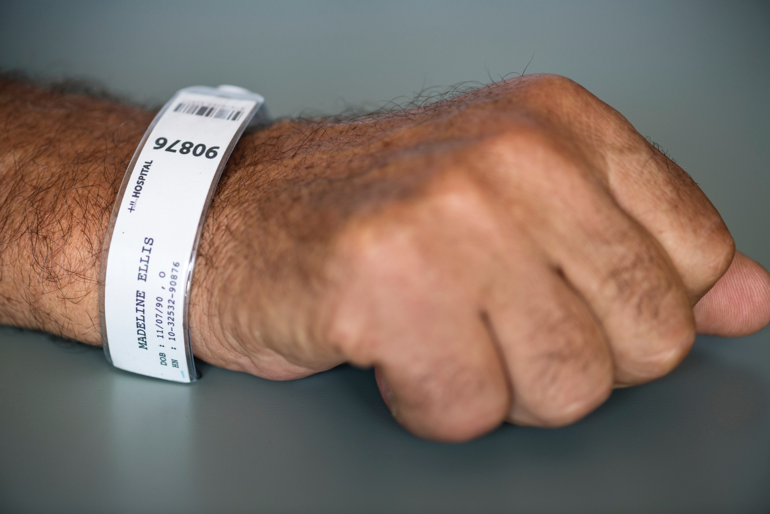 man's wrist with white hospital admission band